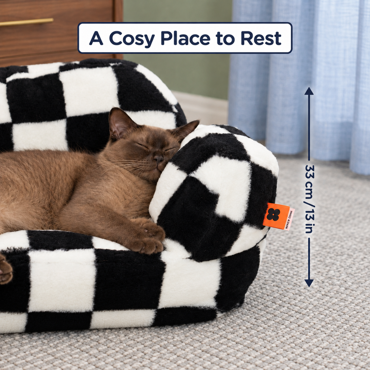 A sleeping cat resting against the checked sofa arm with a 33 cm / 13 in height guide